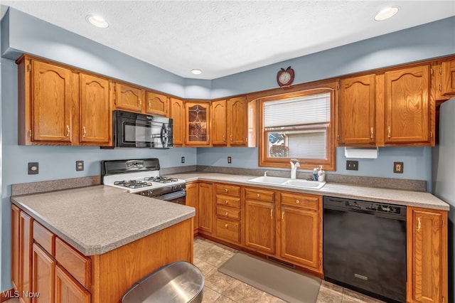 kitchen with black appliances, a textured ceiling, brown cabinetry, and a sink