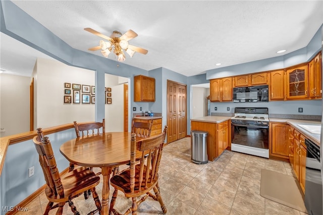 kitchen with brown cabinetry, black microwave, light countertops, and range with gas cooktop