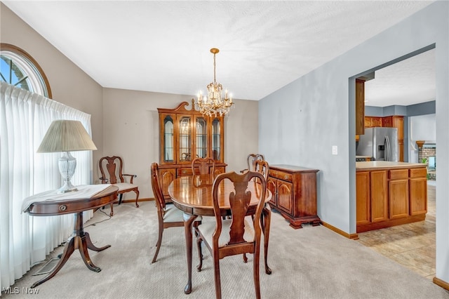 dining space with a chandelier, light carpet, a textured ceiling, and baseboards