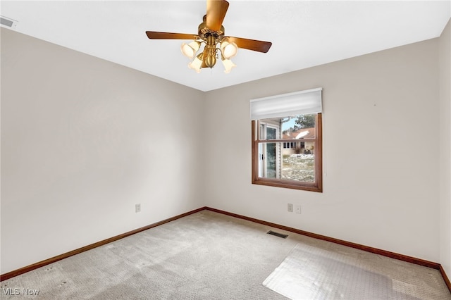 carpeted empty room with baseboards, visible vents, and a ceiling fan