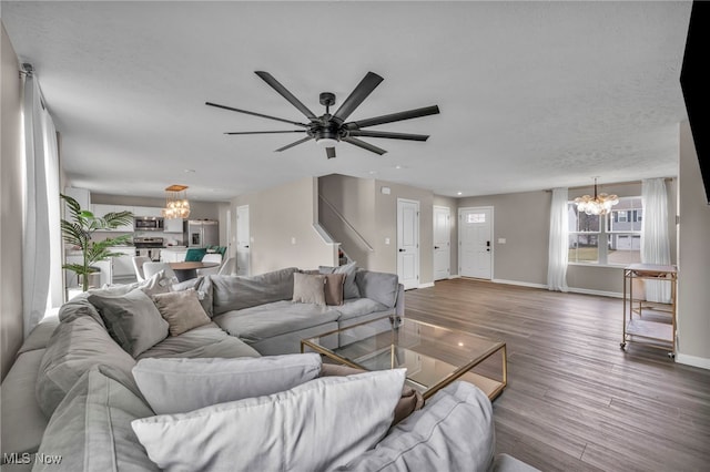 living area with ceiling fan with notable chandelier, wood finished floors, and baseboards