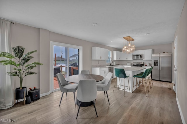 dining room with light wood-style flooring, baseboards, and a notable chandelier