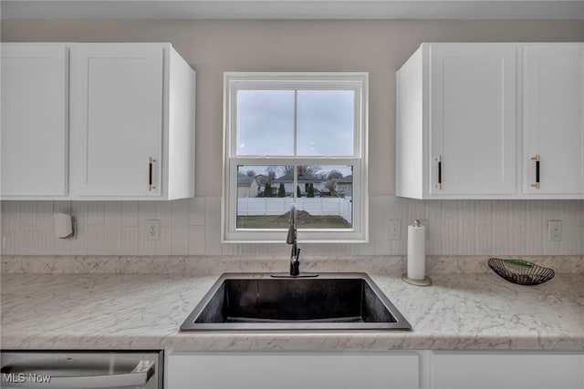 kitchen with dishwasher, a sink, white cabinetry, and light stone countertops