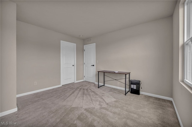 empty room featuring a healthy amount of sunlight, carpet flooring, visible vents, and baseboards