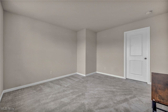 carpeted empty room featuring baseboards