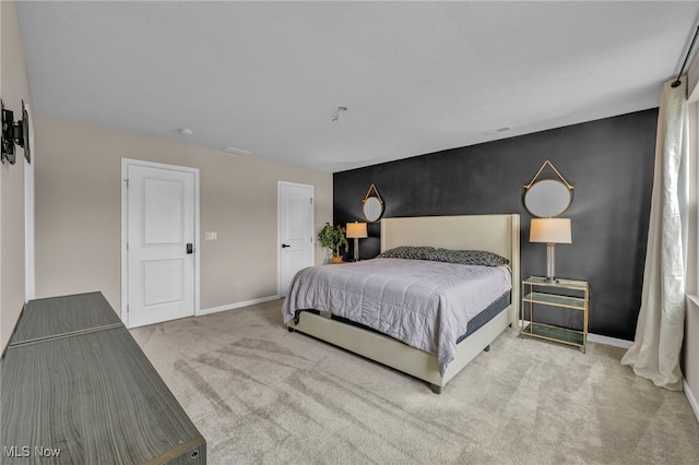 carpeted bedroom with an accent wall and baseboards