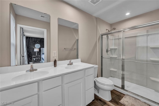 bathroom featuring wood finished floors, a stall shower, a sink, and visible vents