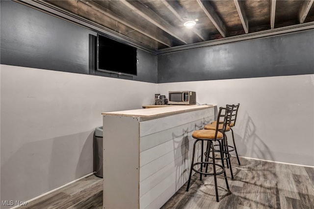 bar with a bar, stainless steel microwave, and wood finished floors