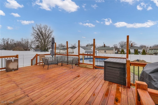 wooden terrace with a fenced backyard and a grill