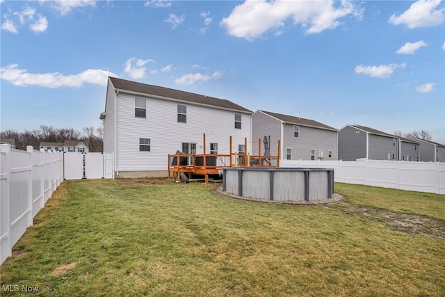 rear view of house with a fenced in pool, a residential view, a fenced backyard, and a yard