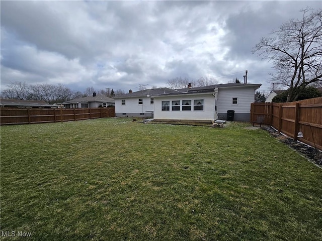 back of house with a lawn and a fenced backyard