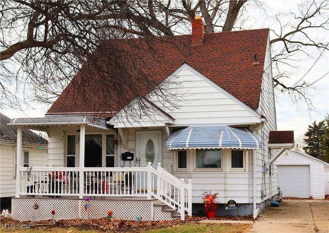 view of front of property featuring a detached garage, a chimney, a shingled roof, covered porch, and an outdoor structure