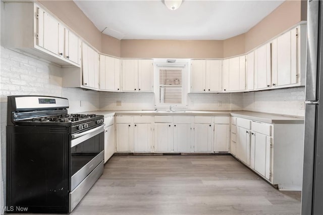 kitchen with light wood-style floors, appliances with stainless steel finishes, light countertops, and decorative backsplash