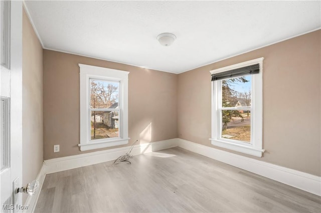 unfurnished room with plenty of natural light, baseboards, and wood finished floors