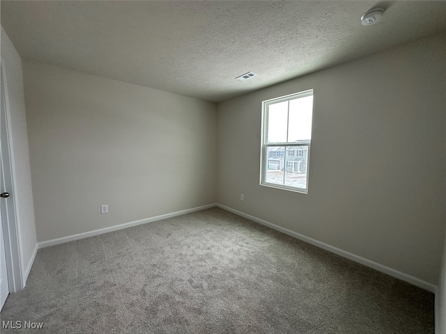 carpeted spare room with visible vents, a textured ceiling, and baseboards