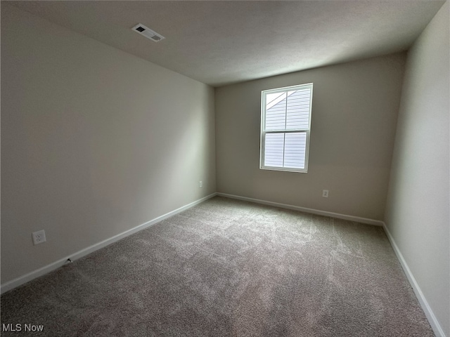 unfurnished room featuring carpet floors, visible vents, and baseboards