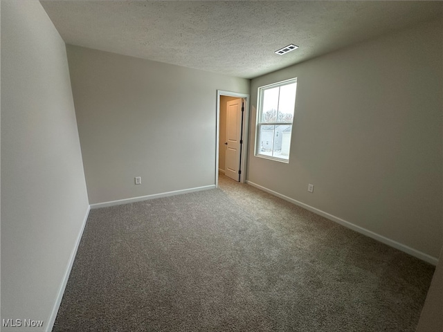 spare room featuring a textured ceiling, carpet flooring, visible vents, and baseboards