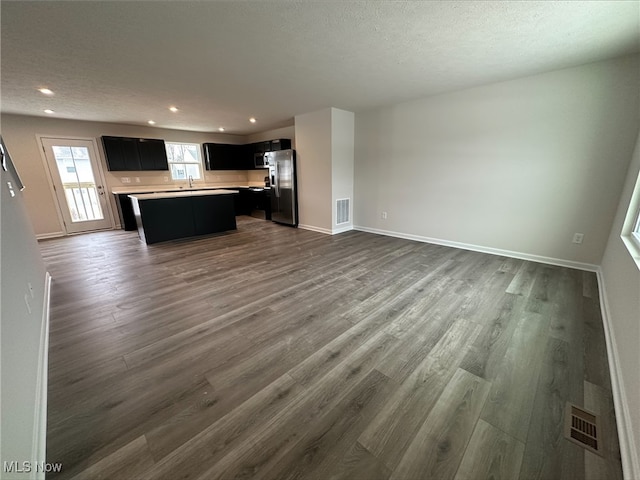 kitchen featuring dark wood-style floors, visible vents, open floor plan, a kitchen island, and stainless steel fridge with ice dispenser