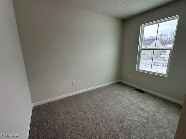 carpeted empty room featuring a textured ceiling, visible vents, and baseboards