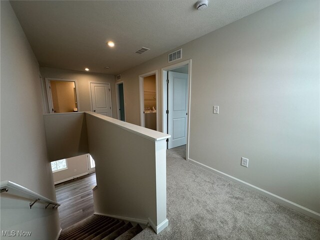 hallway featuring carpet floors, recessed lighting, visible vents, an upstairs landing, and baseboards