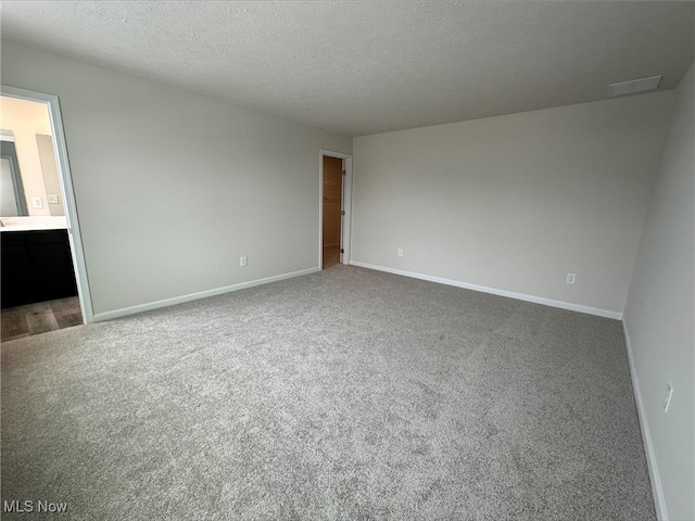 carpeted spare room featuring baseboards and a textured ceiling