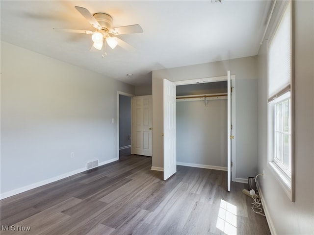 unfurnished bedroom featuring a closet, visible vents, a ceiling fan, wood finished floors, and baseboards