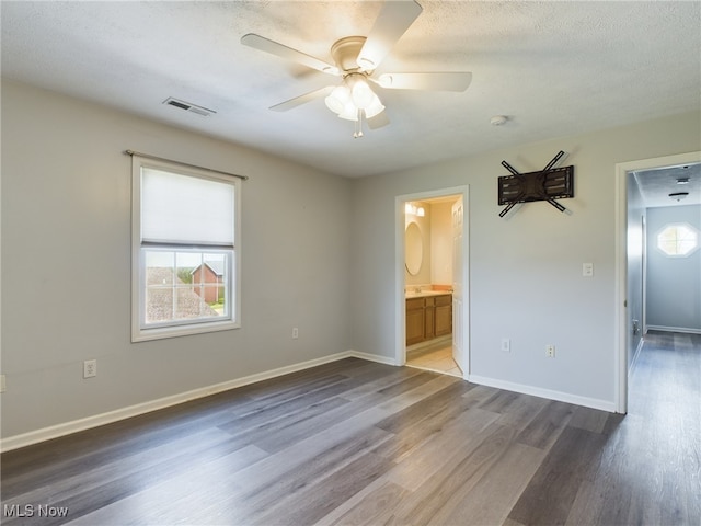 spare room featuring a healthy amount of sunlight, baseboards, visible vents, and wood finished floors