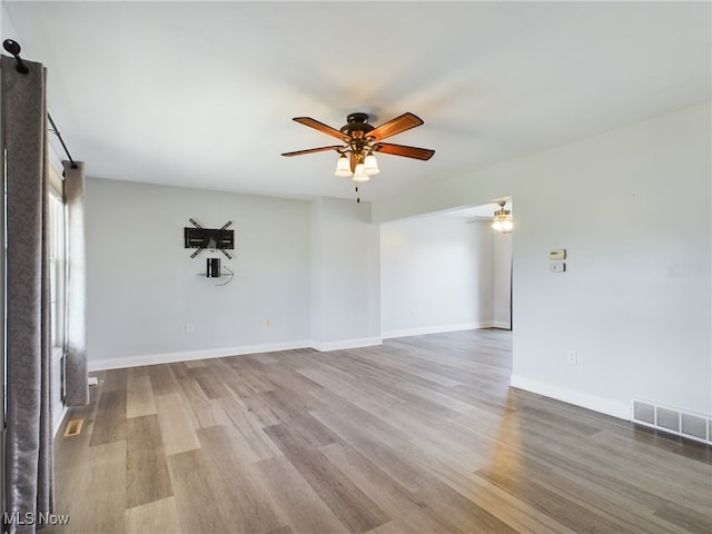 unfurnished room featuring a ceiling fan, wood finished floors, visible vents, and baseboards