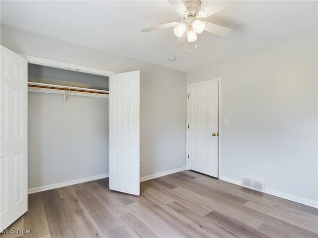 unfurnished bedroom featuring baseboards, a closet, visible vents, and wood finished floors