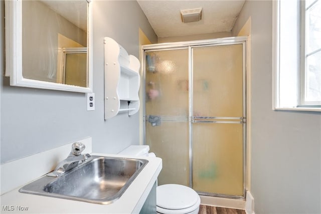 bathroom with toilet, a stall shower, visible vents, and a sink