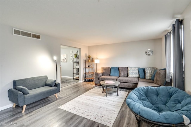 living room featuring baseboards, visible vents, and wood finished floors