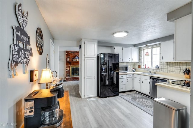 kitchen featuring stainless steel appliances, light countertops, decorative backsplash, light wood-style floors, and white cabinets