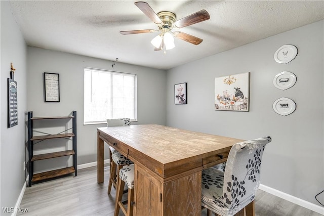 office space featuring a ceiling fan, light wood-type flooring, a textured ceiling, and baseboards