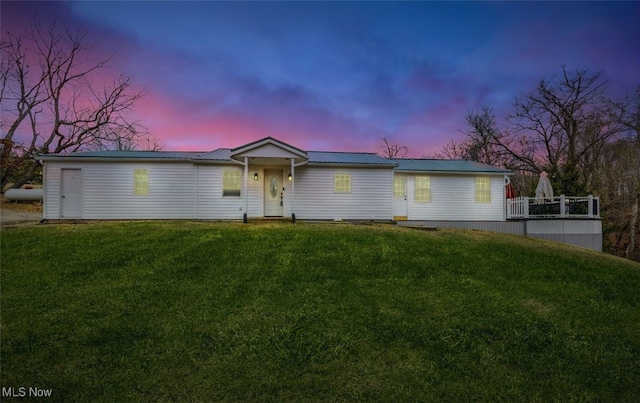 ranch-style house featuring metal roof and a lawn