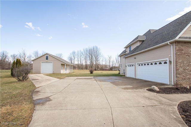 view of side of property with a garage, brick siding, a lawn, and driveway