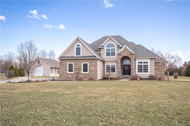 view of front facade featuring brick siding, a front yard, and a shingled roof