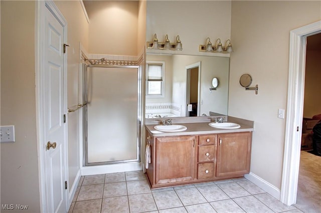 bathroom with double vanity, a stall shower, a sink, and tile patterned floors