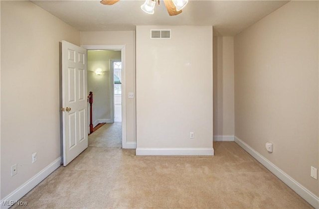 interior space with baseboards, a ceiling fan, visible vents, and light colored carpet