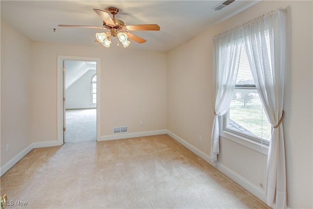 spare room featuring light carpet, plenty of natural light, and visible vents