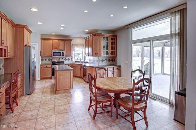 kitchen with stainless steel appliances, recessed lighting, decorative backsplash, glass insert cabinets, and a sink