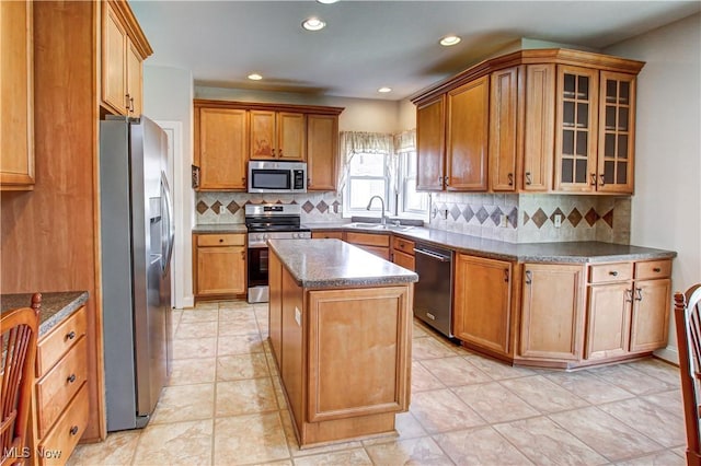 kitchen featuring brown cabinets, appliances with stainless steel finishes, a sink, and a center island