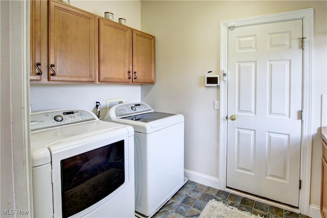 washroom with stone finish floor, washing machine and clothes dryer, cabinet space, and baseboards