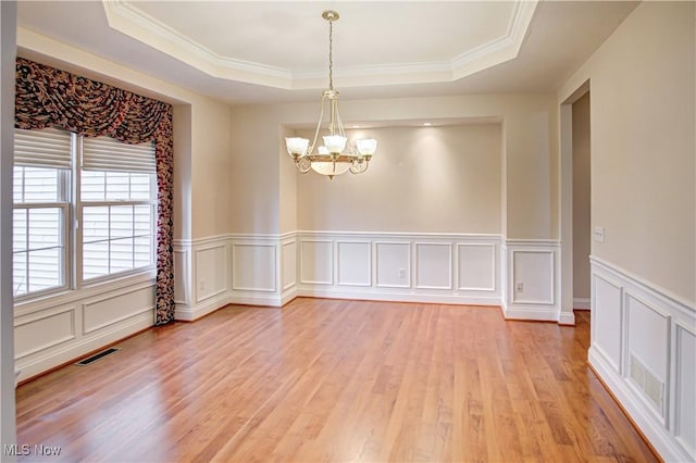 unfurnished room with a chandelier, a raised ceiling, visible vents, and light wood-style floors