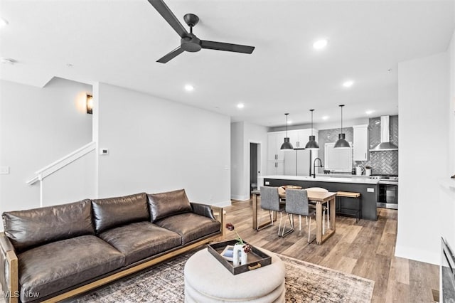 living room with light wood-style floors, recessed lighting, ceiling fan, and baseboards