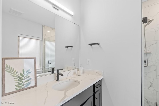 full bath featuring visible vents, a marble finish shower, and vanity