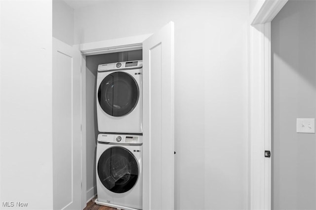 laundry area featuring laundry area, stacked washer / dryer, and wood finished floors