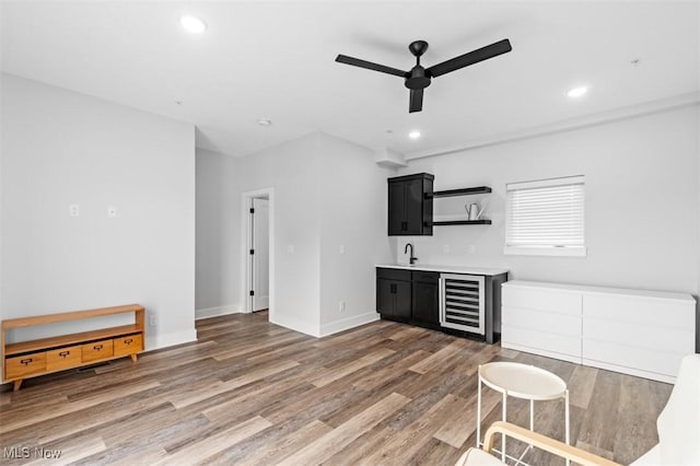 interior space with beverage cooler, a ceiling fan, wet bar, light wood-type flooring, and recessed lighting