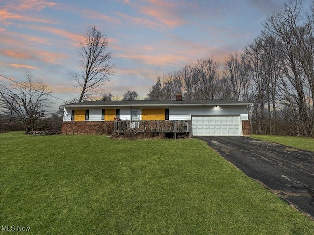 ranch-style home featuring driveway, a garage, a front lawn, and brick siding