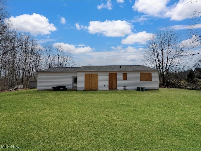 rear view of house featuring central AC and a lawn