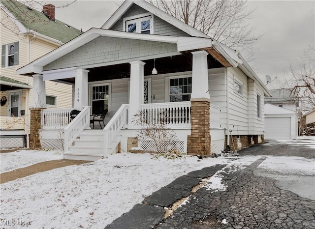 bungalow-style home featuring a garage, a porch, and an outbuilding